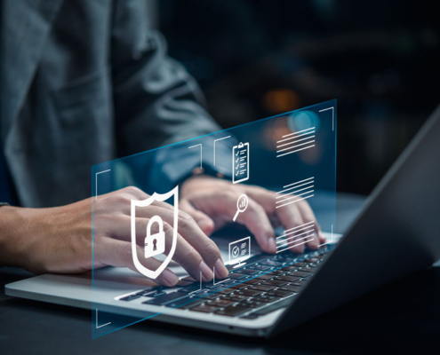 A man typing on a laptop with a graphic representing cybersecurity.