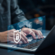 A man typing on a laptop with a graphic representing cybersecurity.
