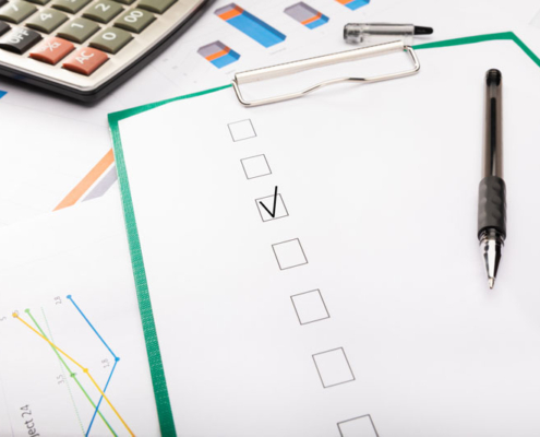 A checklist and pen on paper with one box marked off.