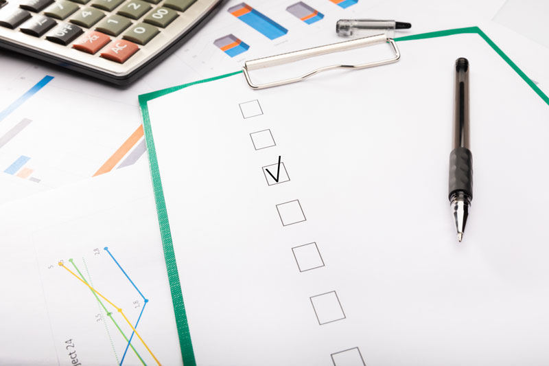 A checklist and pen on paper with one box marked off.