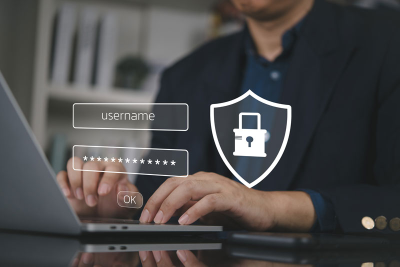 A man typing his username and password into his locked laptop.