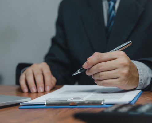 A man filling out a document on a clipboard with a pen.
