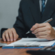 A man filling out a document on a clipboard with a pen.