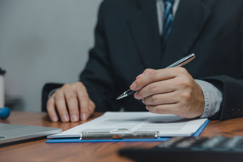 A man filling out a document on a clipboard with a pen.