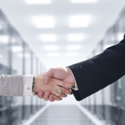 A businessman and businesswoman shaking hands in a server room.