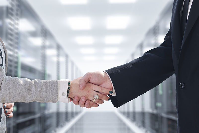 managed-security A businessman and businesswoman shaking hands in a server room.